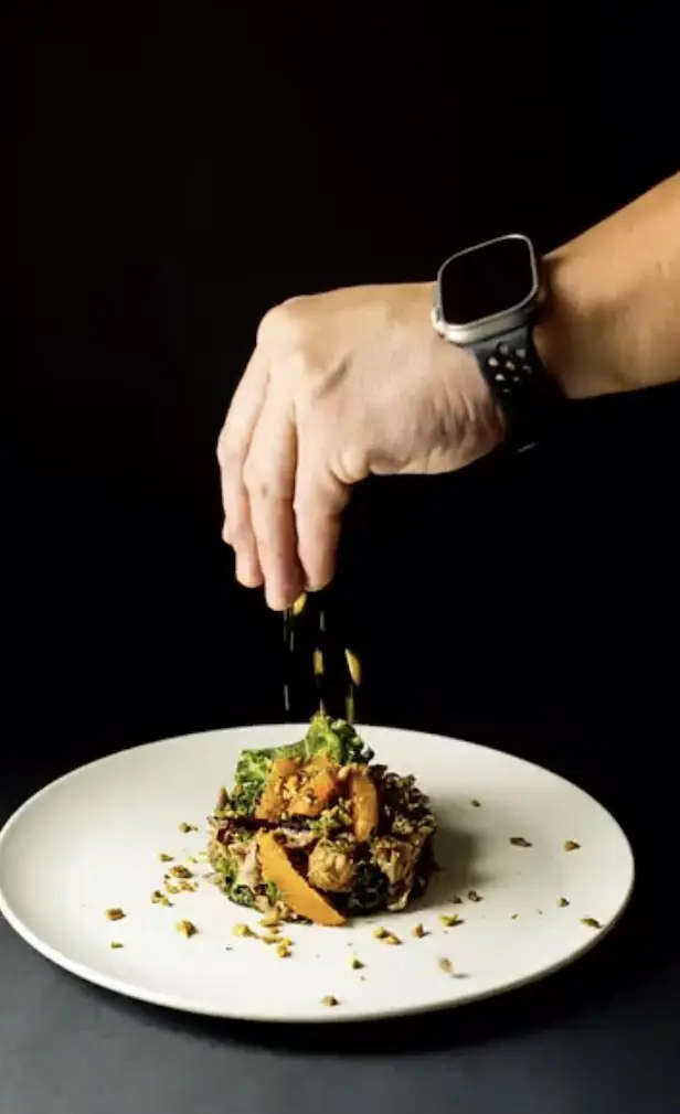 Chef Paul Aceto finishing a plated dish with pistachio