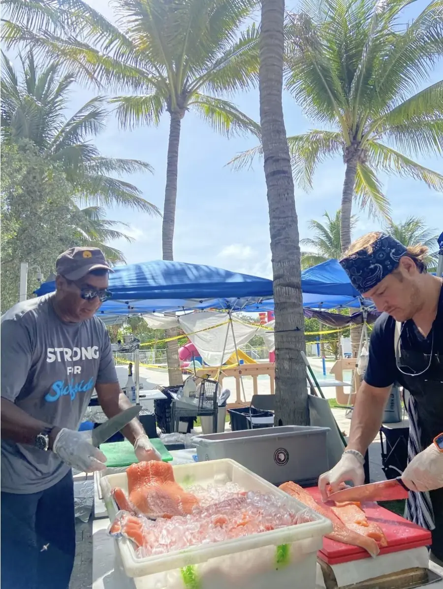 Chef Paul portioning salmon at an outdoor relief station in Surfside